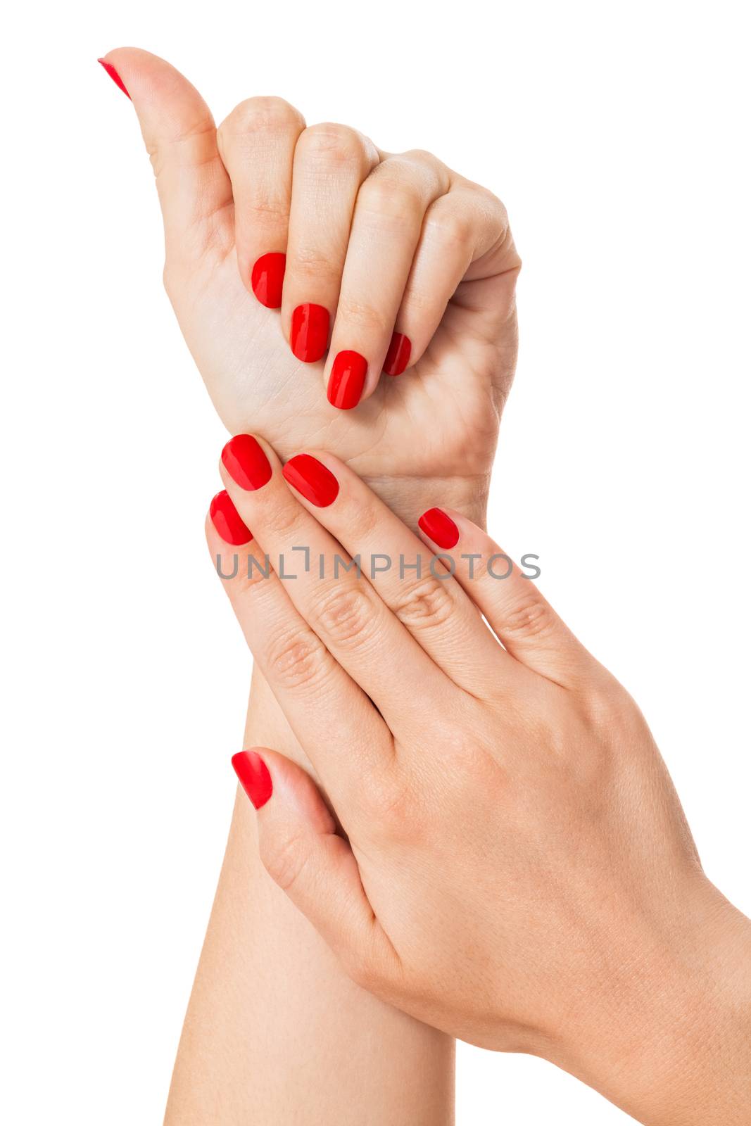 Woman with beautiful manicured red fingernails gracefully crossing her hands to display them to the viewer on a white background in a fashion, glamour and beauty concept