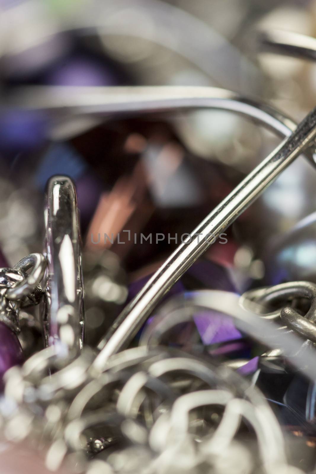 Close up of three attractive shiny purple beads attached by silver chains on an item of jewellery in a fashion and handicraft concept