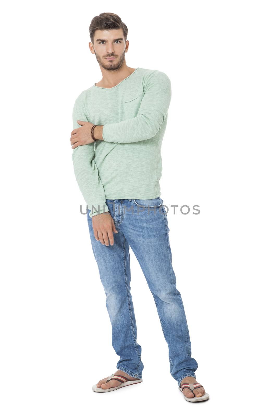 Handsome confident relaxed handsome young man with a beard posing with his hands in his pockets in jeans and slip slops, isolated on white