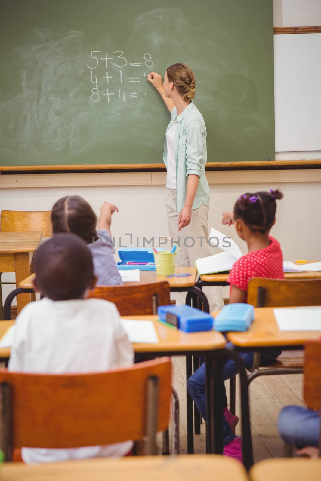 Teacher writing mathematics on board at the elementary school