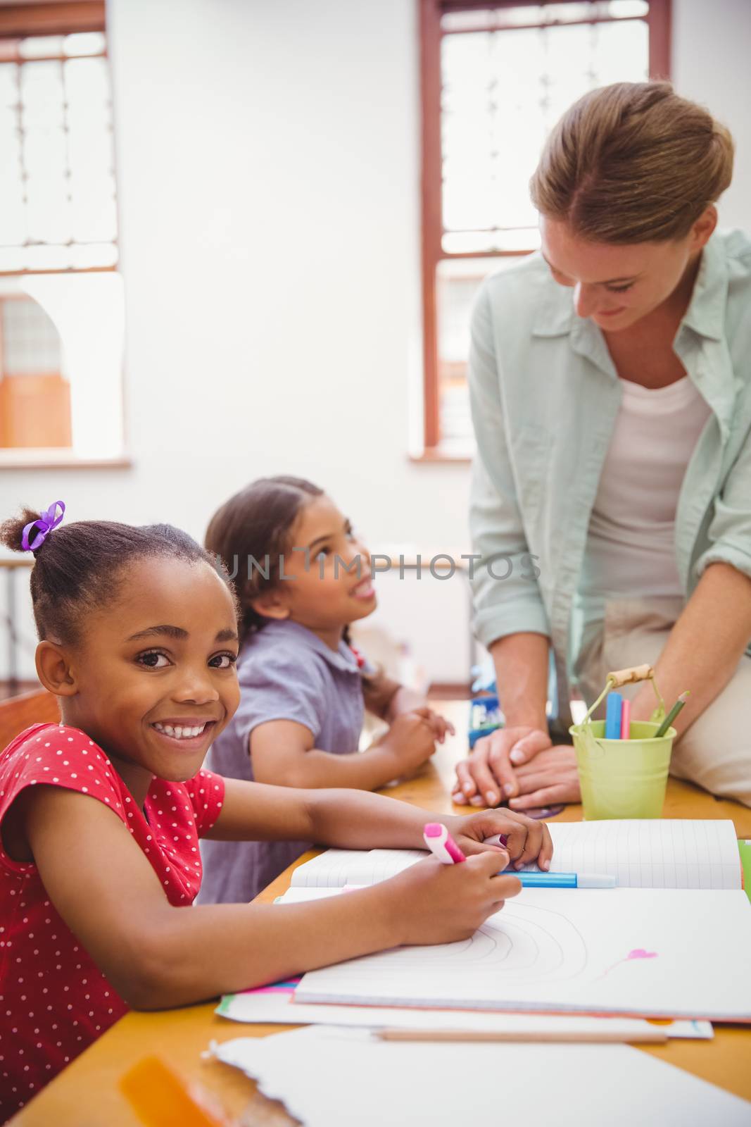 Cute pupils drawing at their desks one smiling at camera by Wavebreakmedia