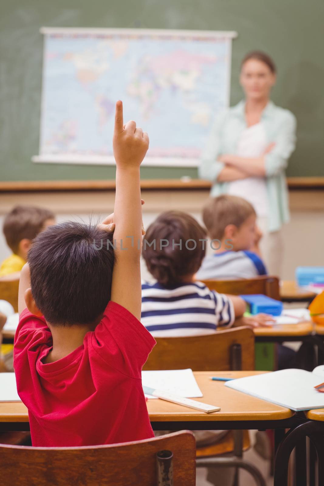 Pupil raising hand during geography lesson in classroom at the elementary school