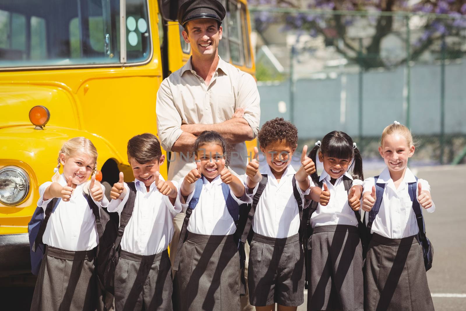 Cute pupils with their school bus driver outside the elementary school