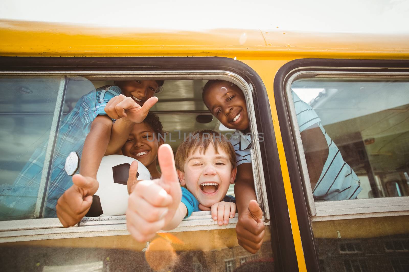 Cute pupils smiling at camera in the school bus outside the elementary school