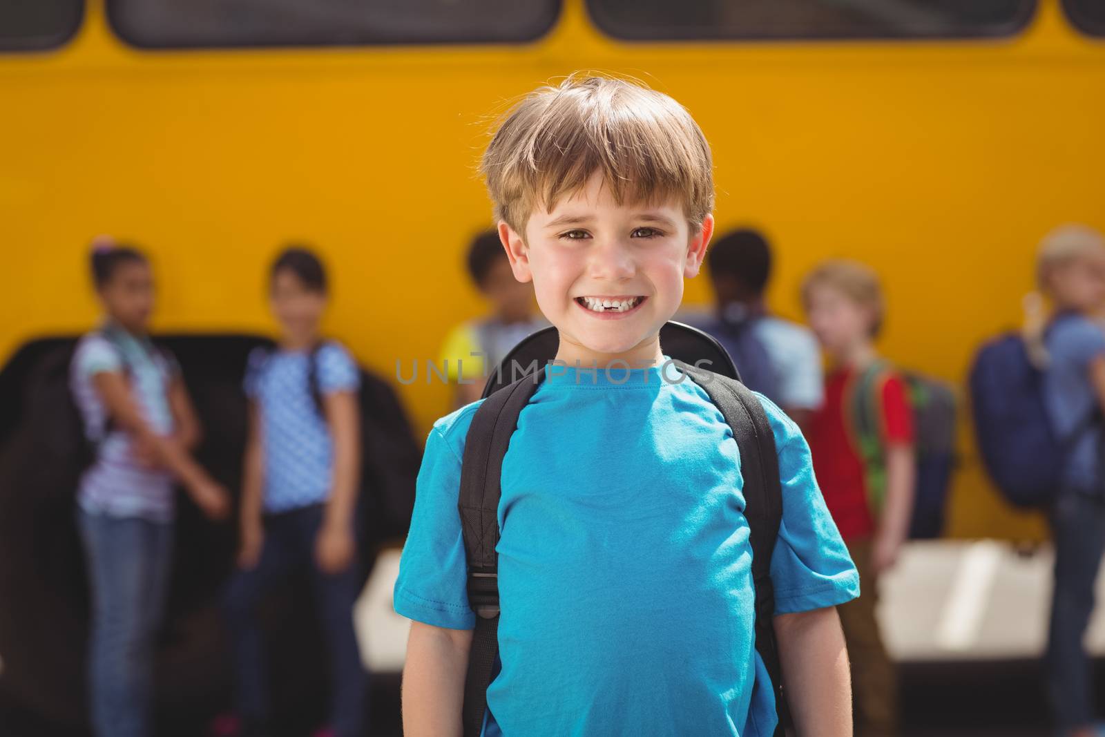 Cute pupils smiling at camera by the school bus by Wavebreakmedia