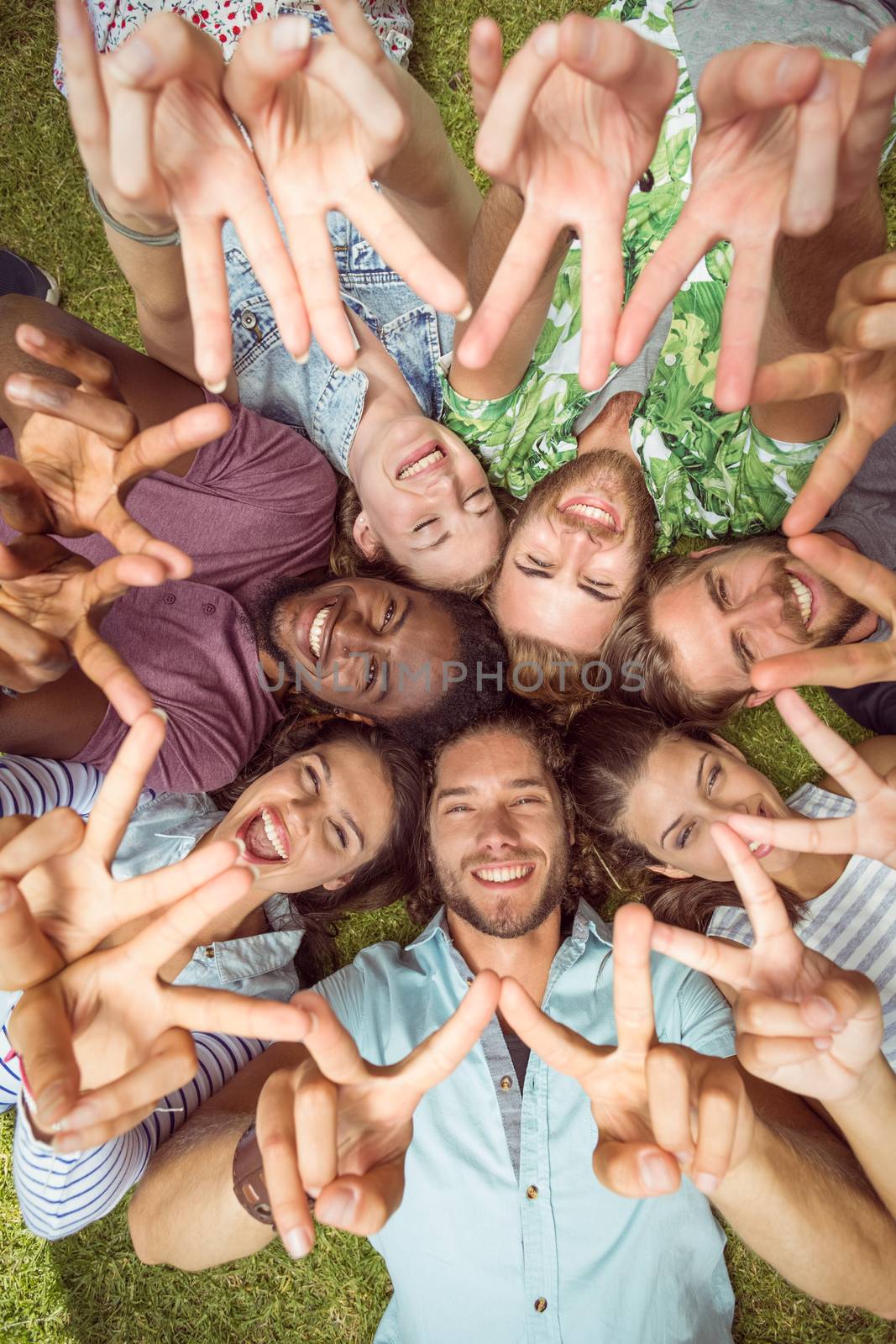 Happy young friends lying on grass by Wavebreakmedia