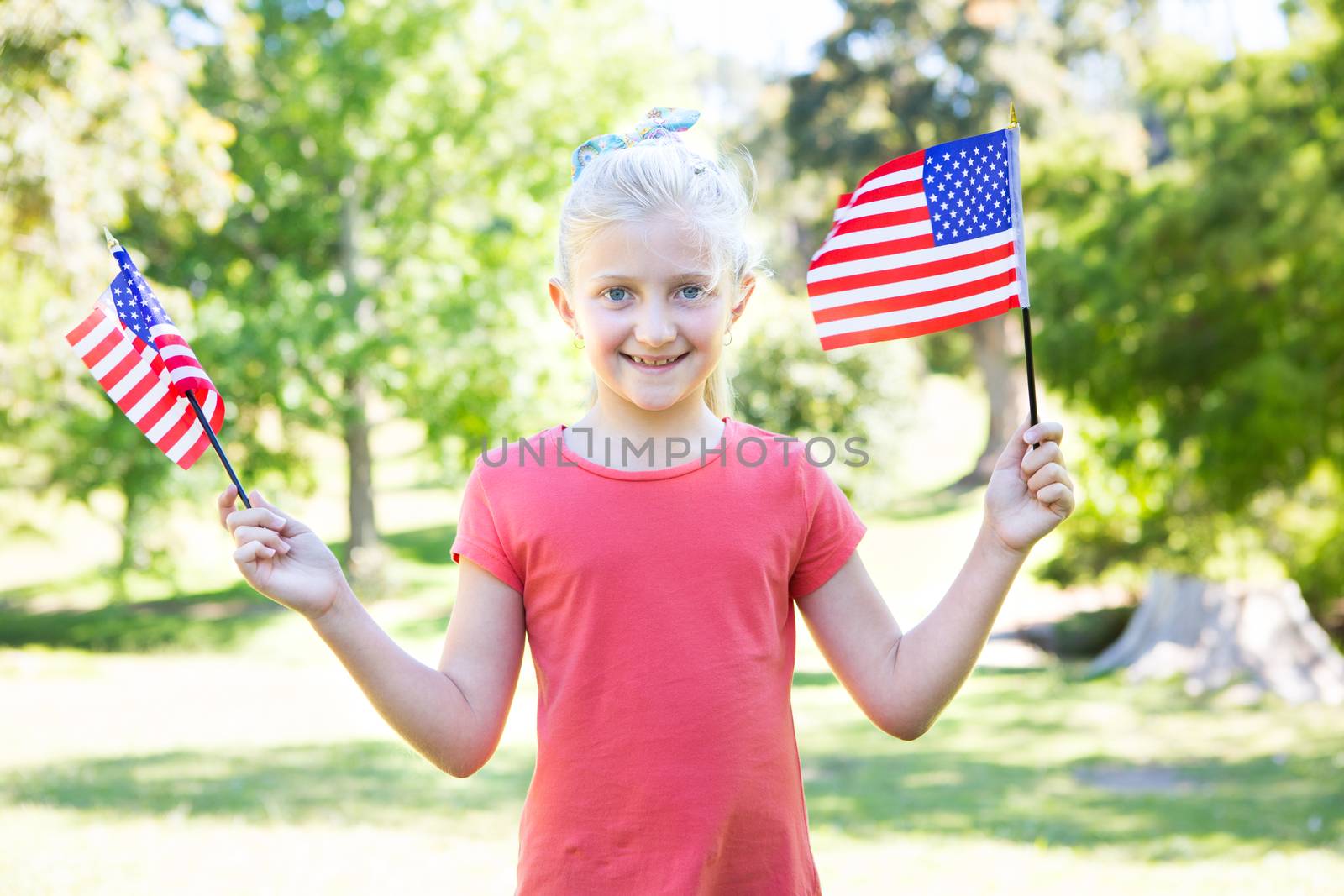 Little girl waving american flag on a sunny day