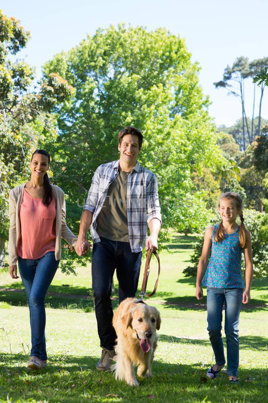 Happy family walking their dog in the park by Wavebreakmedia