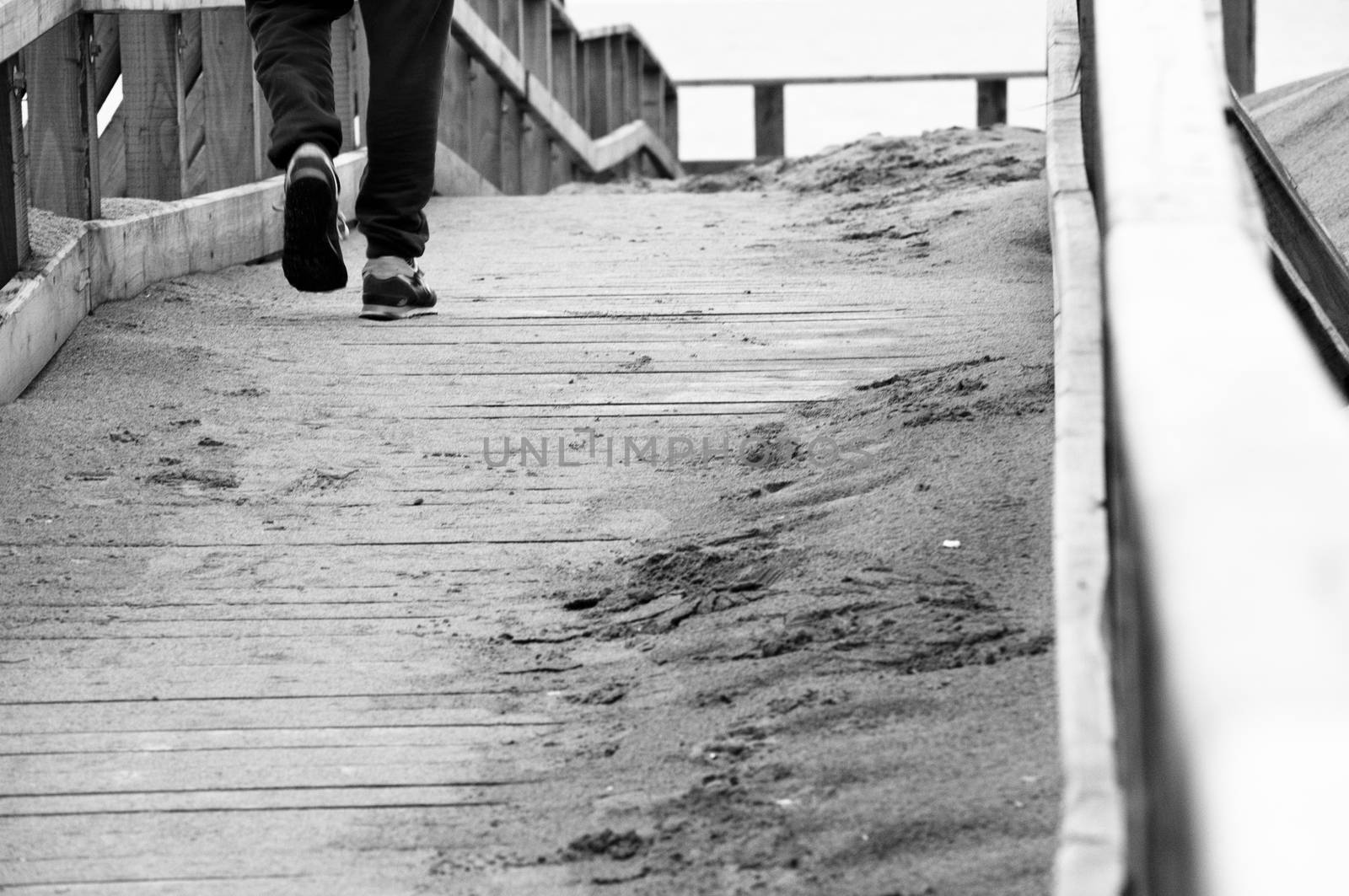 a lonely boy walking on a wooden bridge near the sea