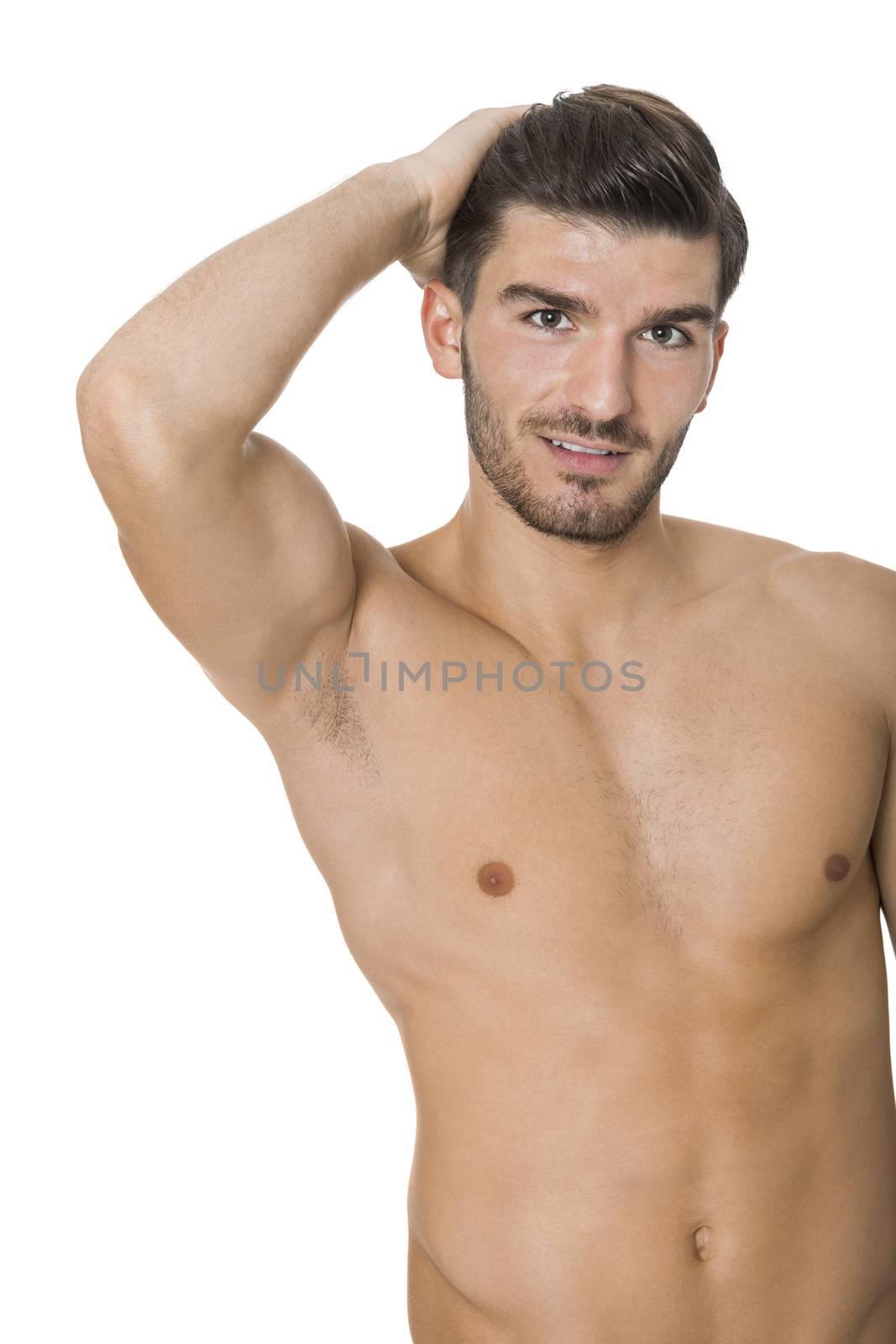 Handsome shirtless naked bearded young man standing looking intently at the camera with his hand to his chin in a sensual sexy pose, isolated on white