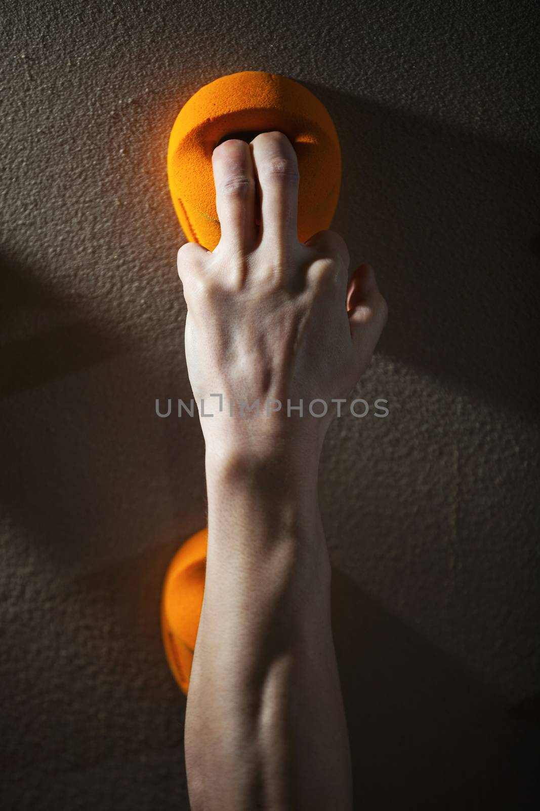 Rock climber gripping handhold with two fingers by photobac