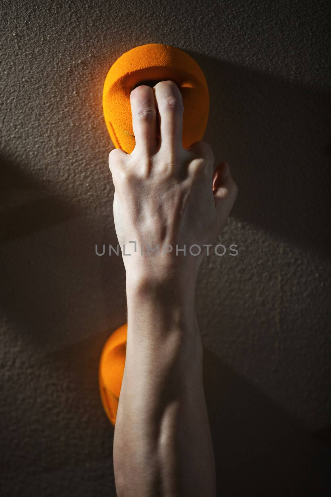 Cropped view of rock climber gripping handhold with two fingers