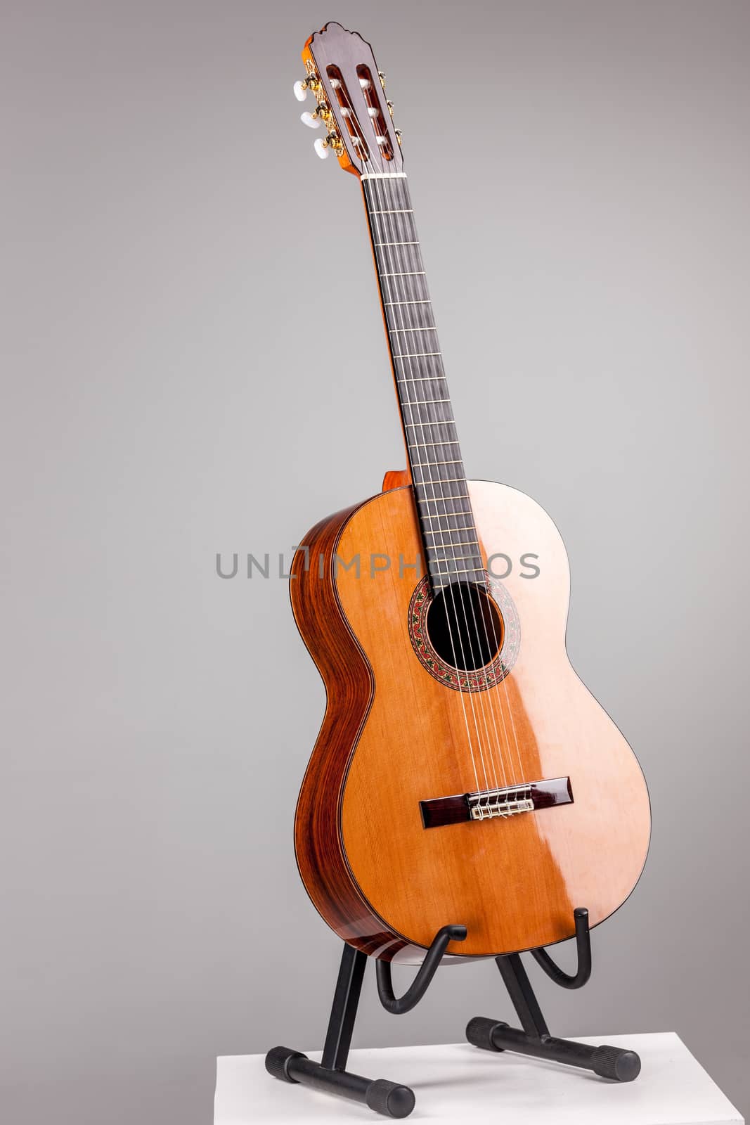 Isolated on gray brown acoustic guitar  on a stand