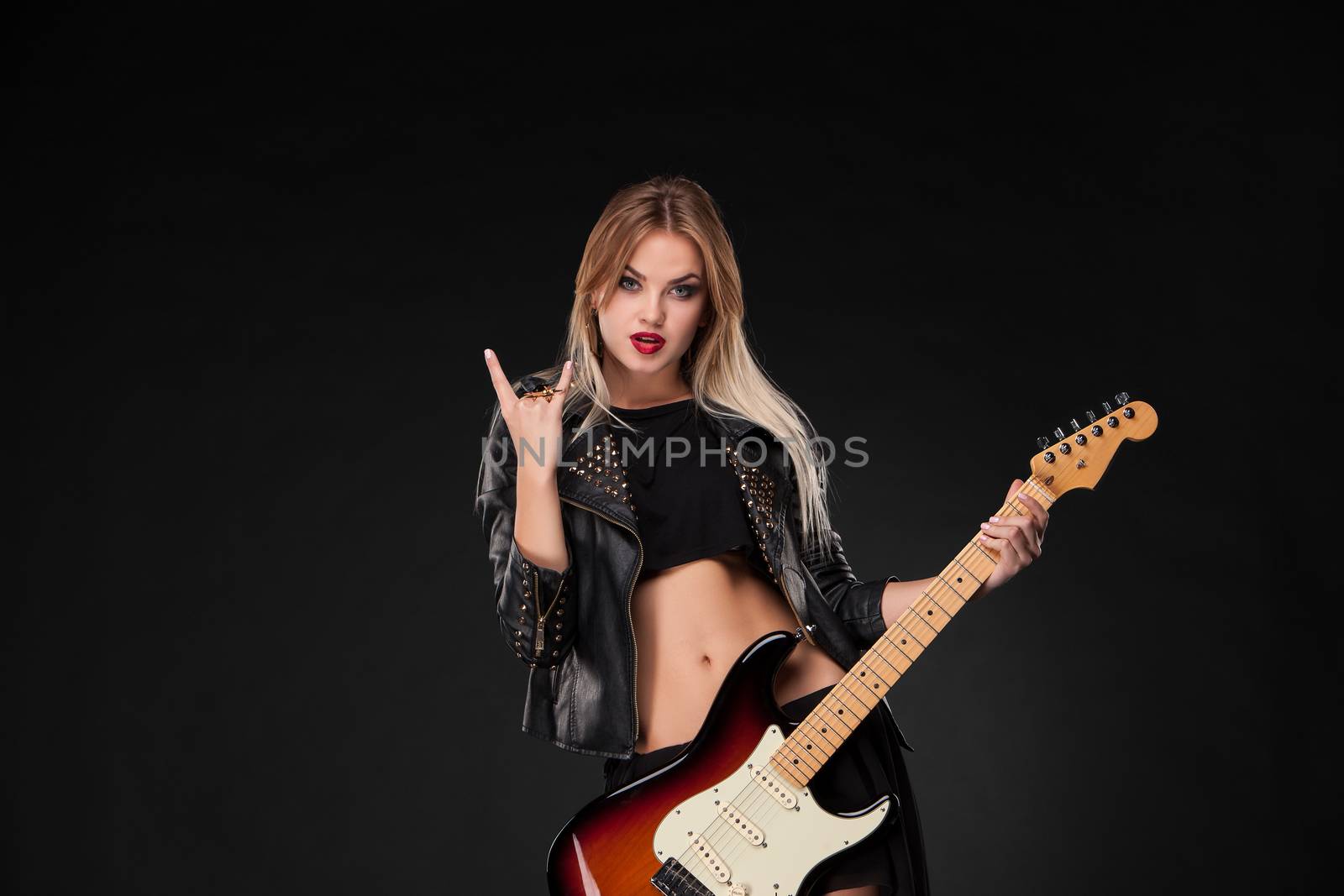 Beautiful blonde girl playing guitar in rock style on a black background