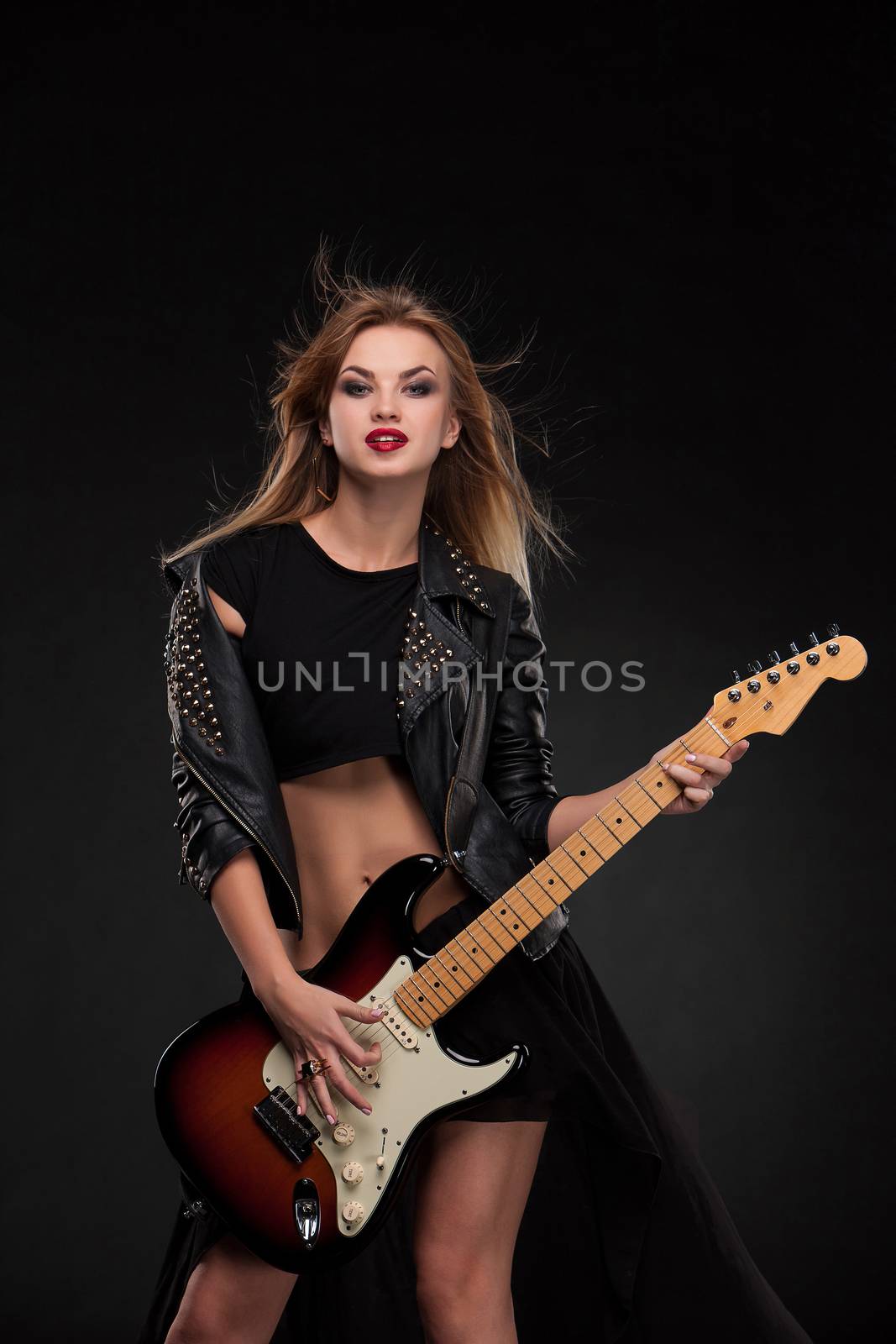 Beautiful blonde girl playing guitar in rock style on a black background