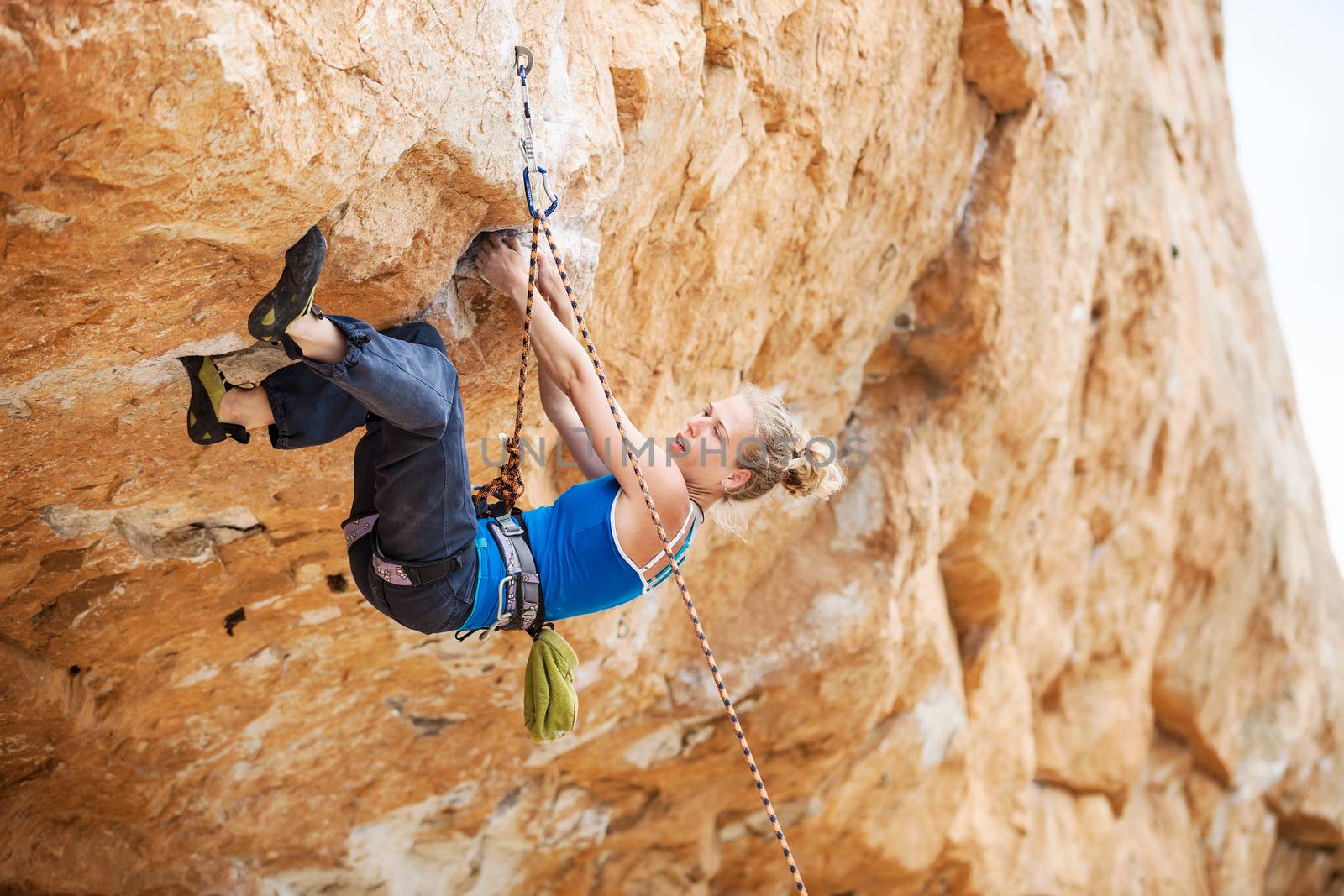 Rock climber struggling to make next movement up by photobac