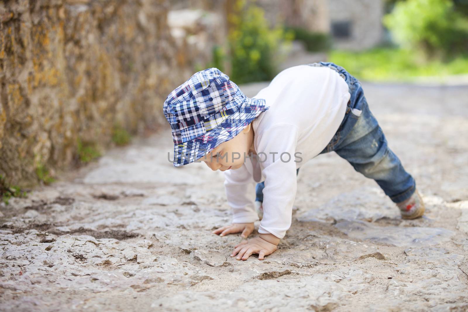 Little boy crawling on stone paved sidewalk by photobac