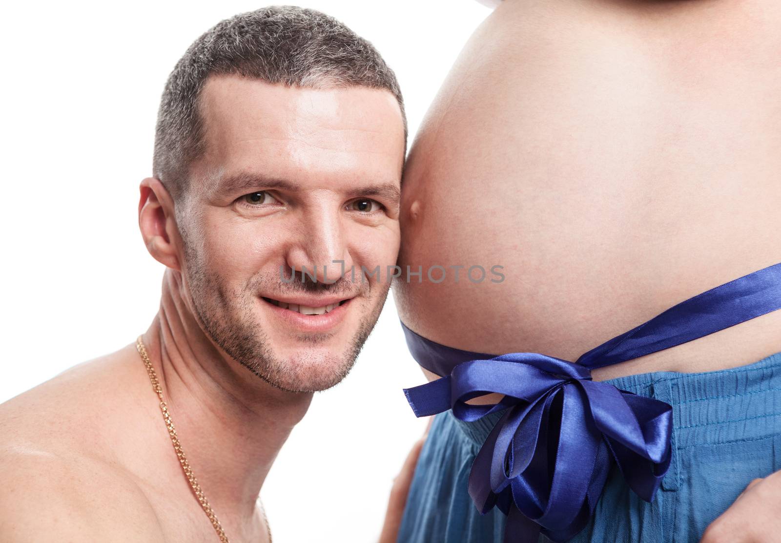 Young man listening to wife's pregnant tummy by photobac