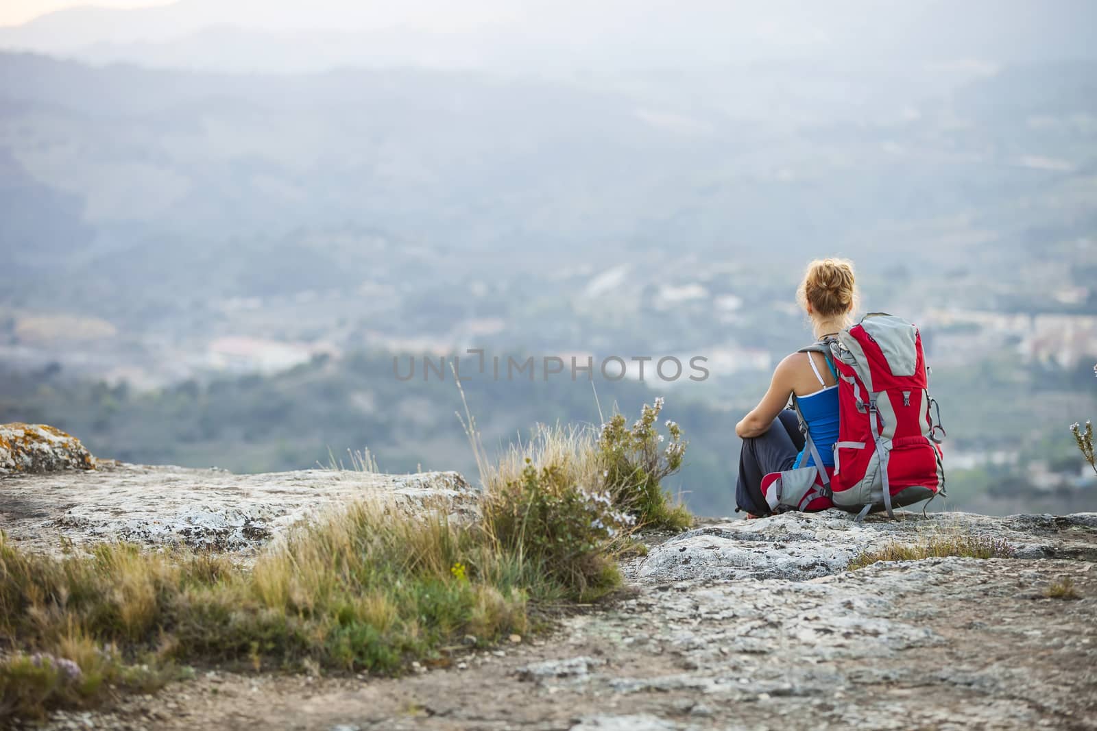 Woman tourist sitting on top of a mountain by photobac