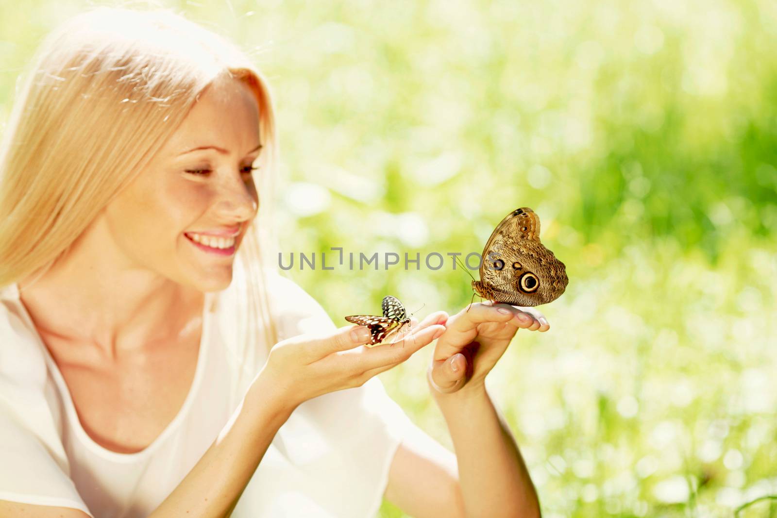 Beautiful young happy Woman playing with butterfly outdoors