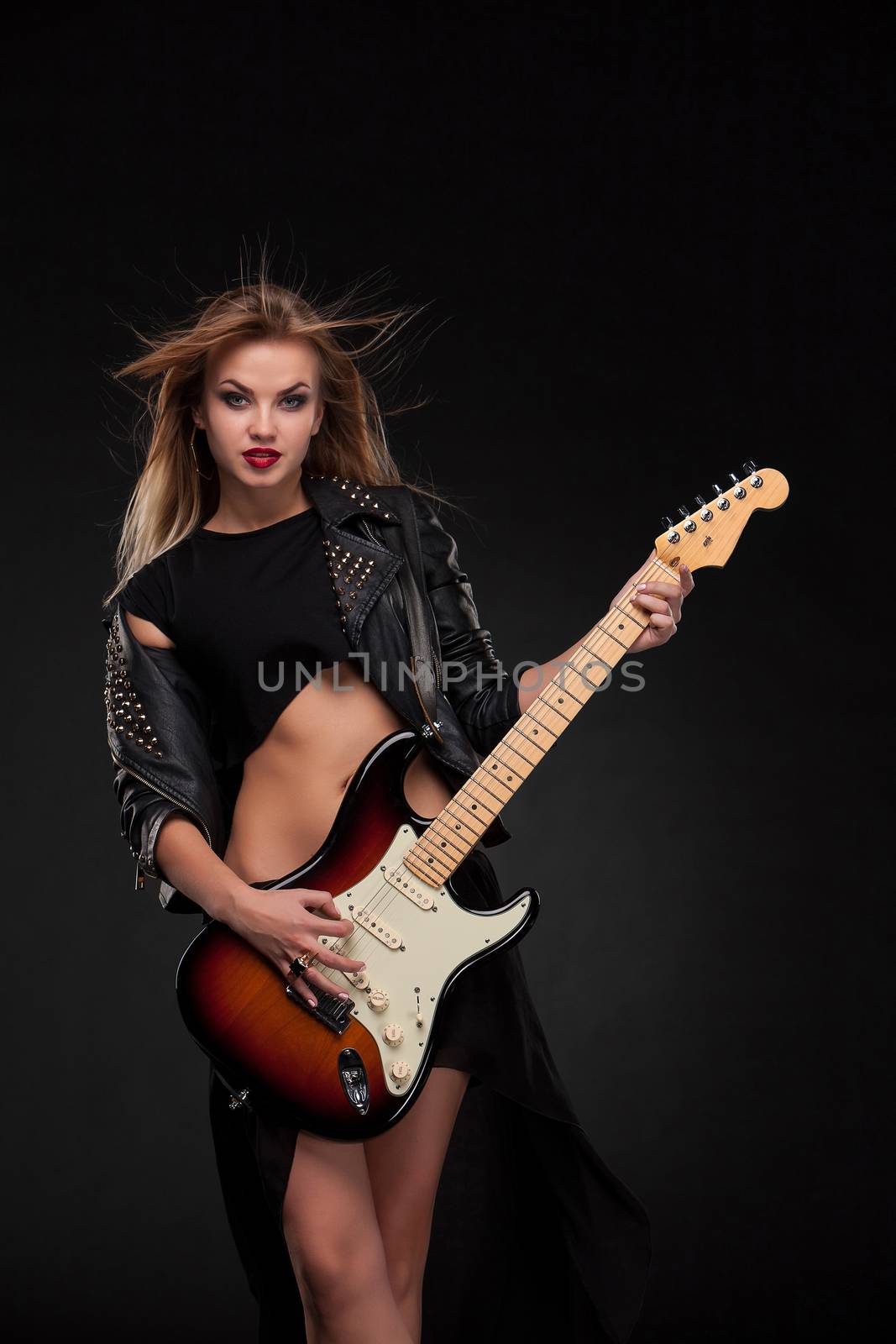 Beautiful blonde girl playing guitar in rock style on a black background