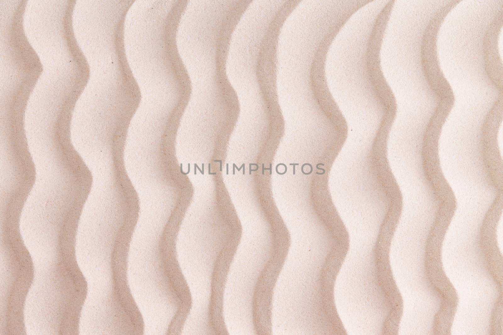 Decorative patterned golden beach sand background with wavy lines reminiscent of the ripples in the sea in a nautical or marine themed concept