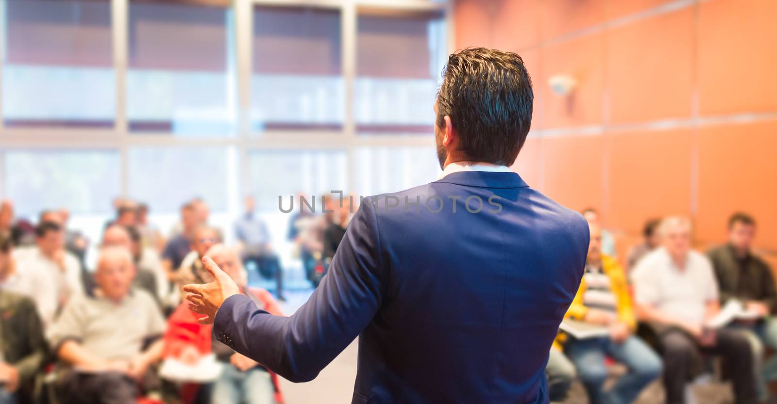 Speaker at Business Conference with Public Presentations. Audience at the conference hall. Entrepreneurship club. Rear view. Horisontal composition. Background blur.