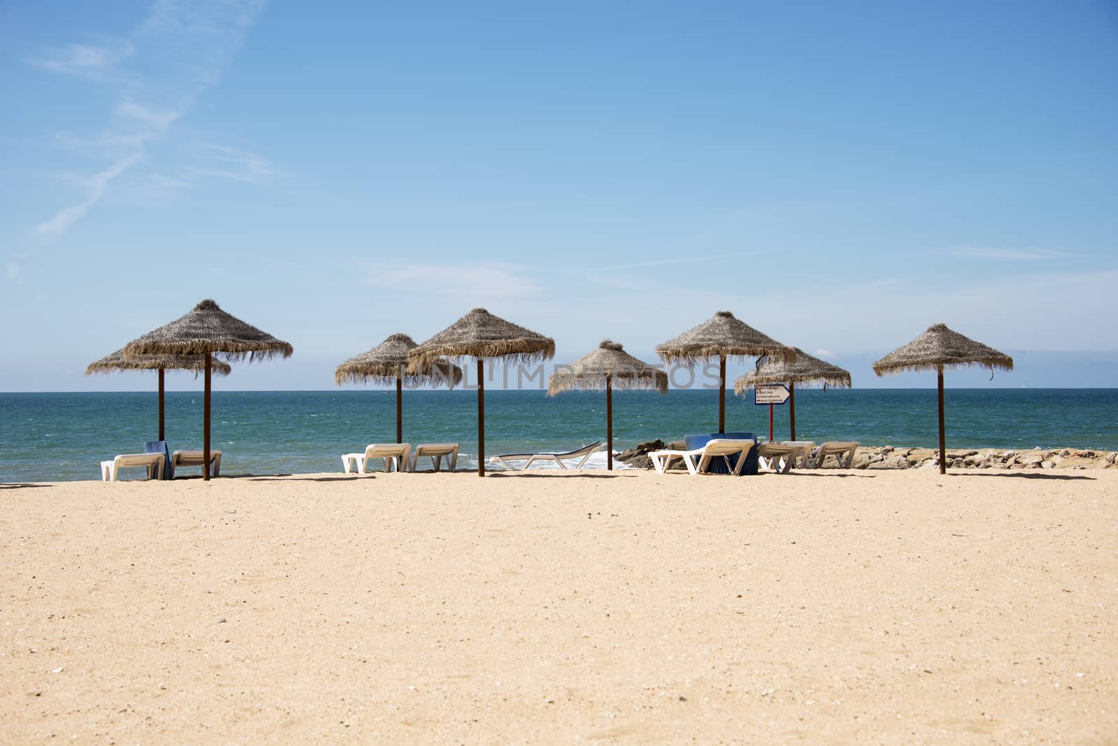 tropical parasols on the algarve beach with the sea as background