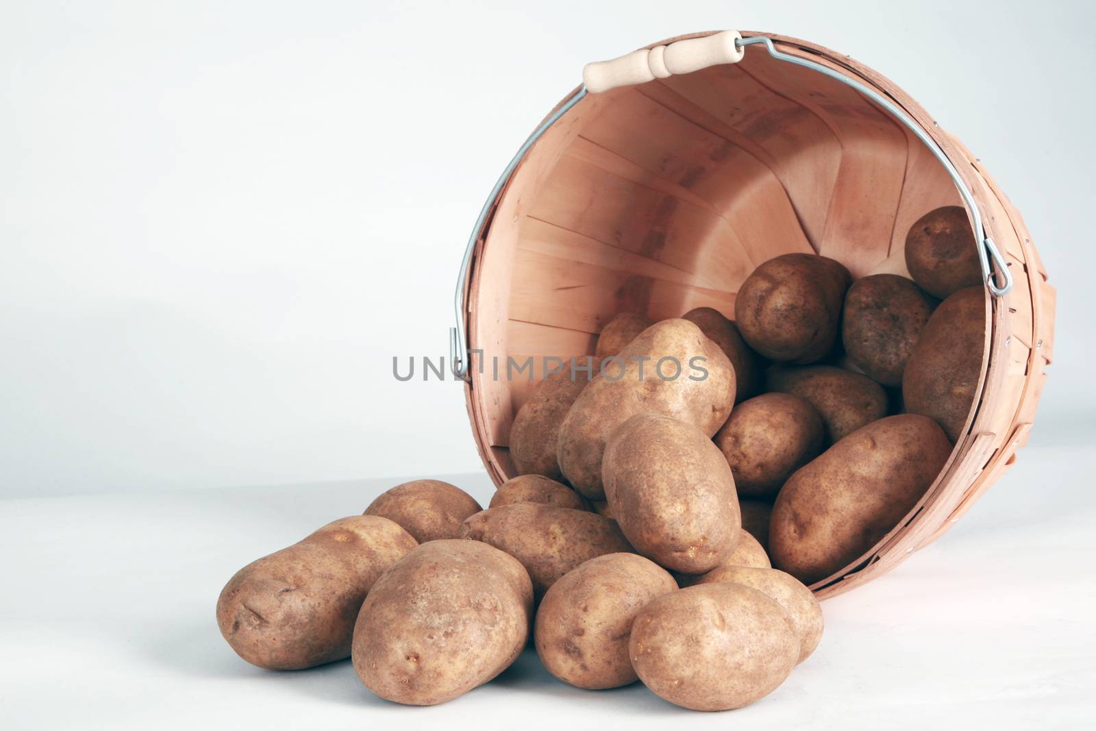 Whole potatoes coming out of a basket. by jimmartin