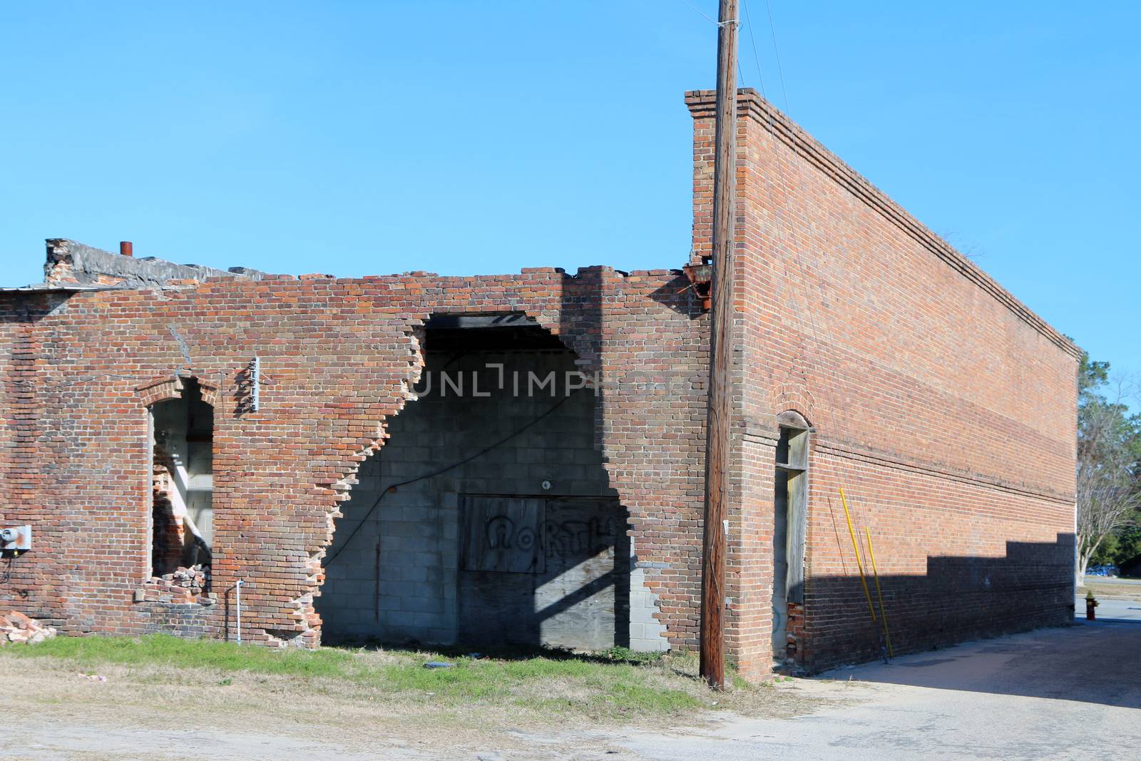 Abandoned and damaged brick building with large hole in the rear wall.