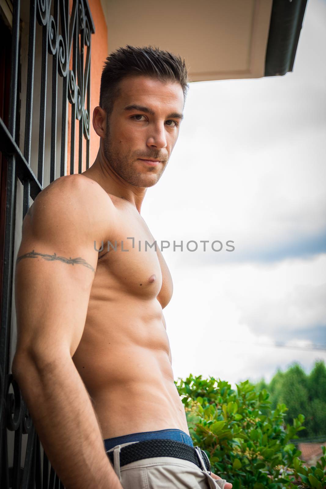 Handsome shirtless muscular young man outdoor, looking at camera