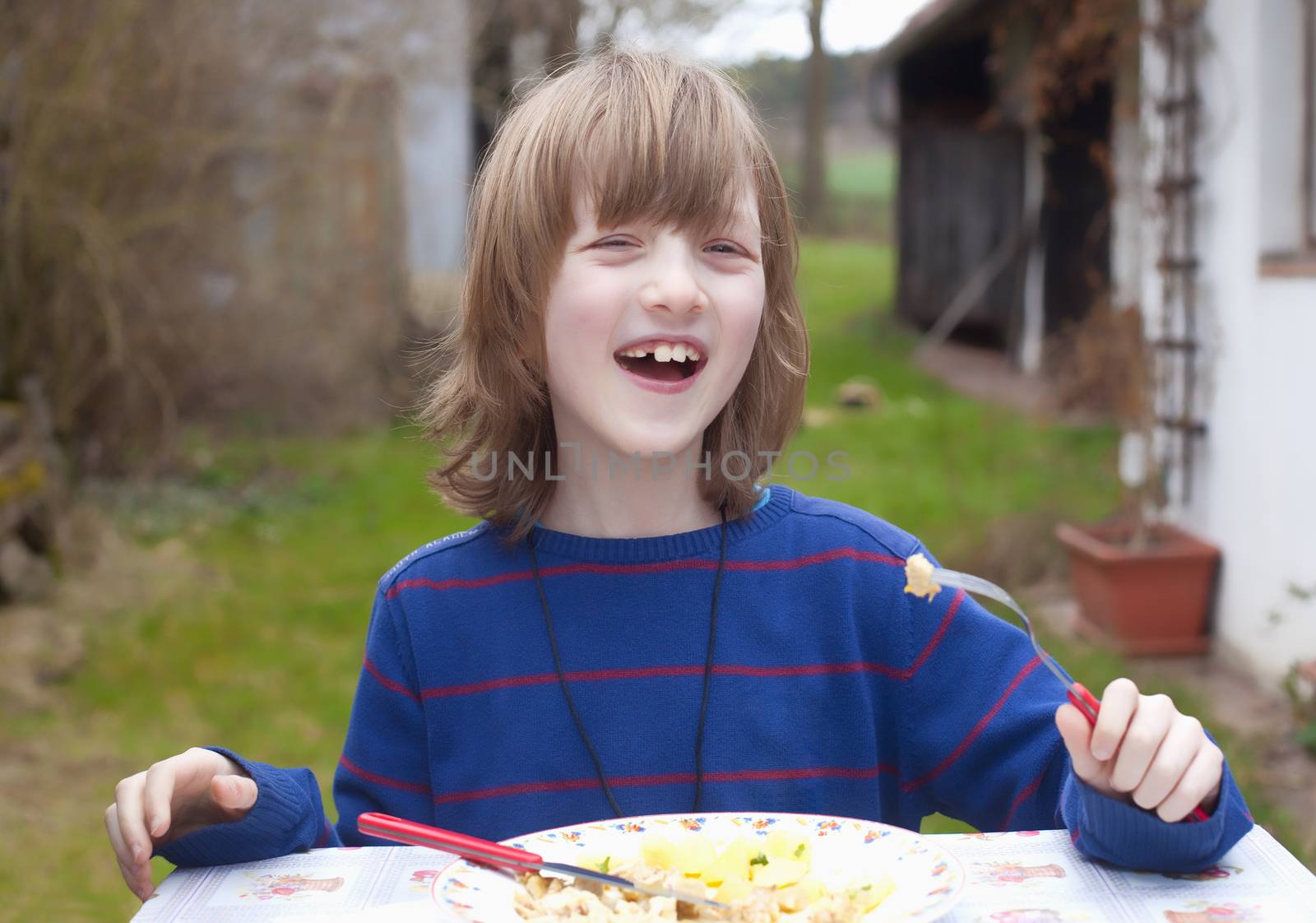Boy with Blond Hair Eating Outdoors Smiling