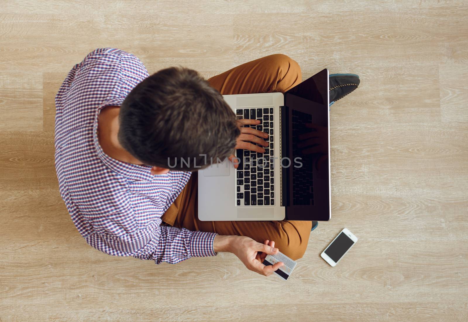 Online shopping - top view of man sitting on the floor and worki by vlad_star