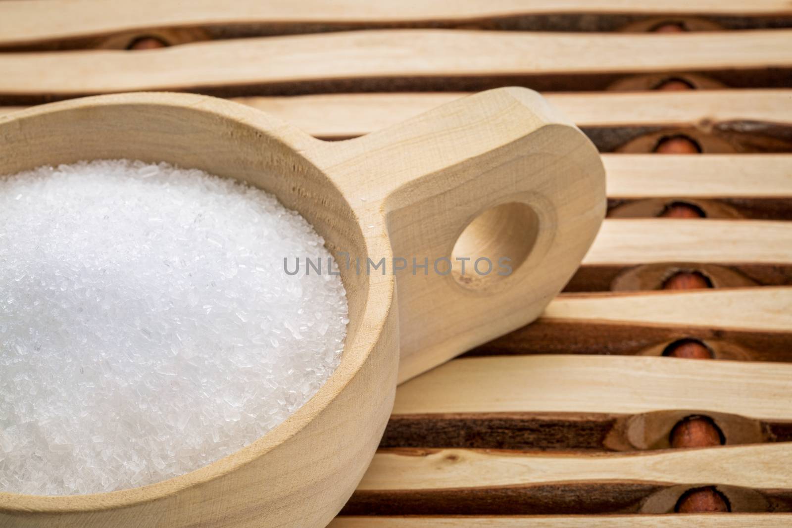 Magnesium sulfate (Epsom salts) in a rustic wooden scoop - relaxing bath concept