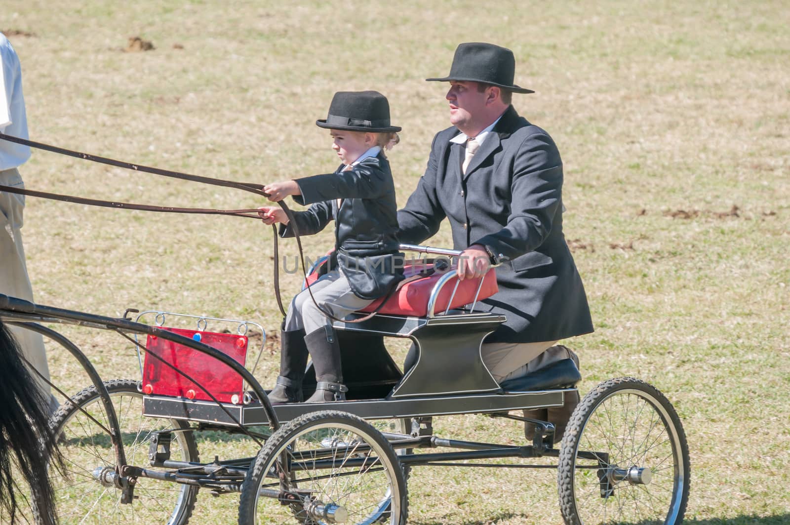 BLOEMFONTEIN, SOUTH AFRICA - APRIL 28, 2015: Young girl and father on a horse-drawn cart during the South African National Championships at the Bloem Show