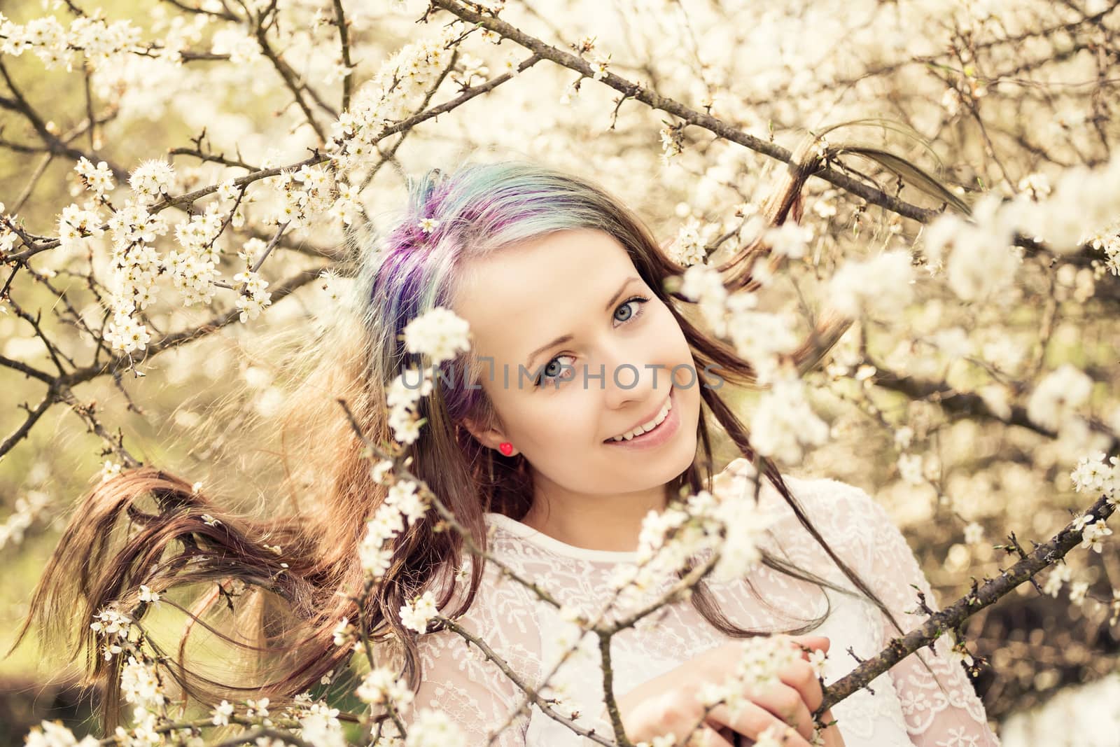 Portrait of cheerful fashionable woman in spring blooming tree, with flowers in hair, retro vintage color