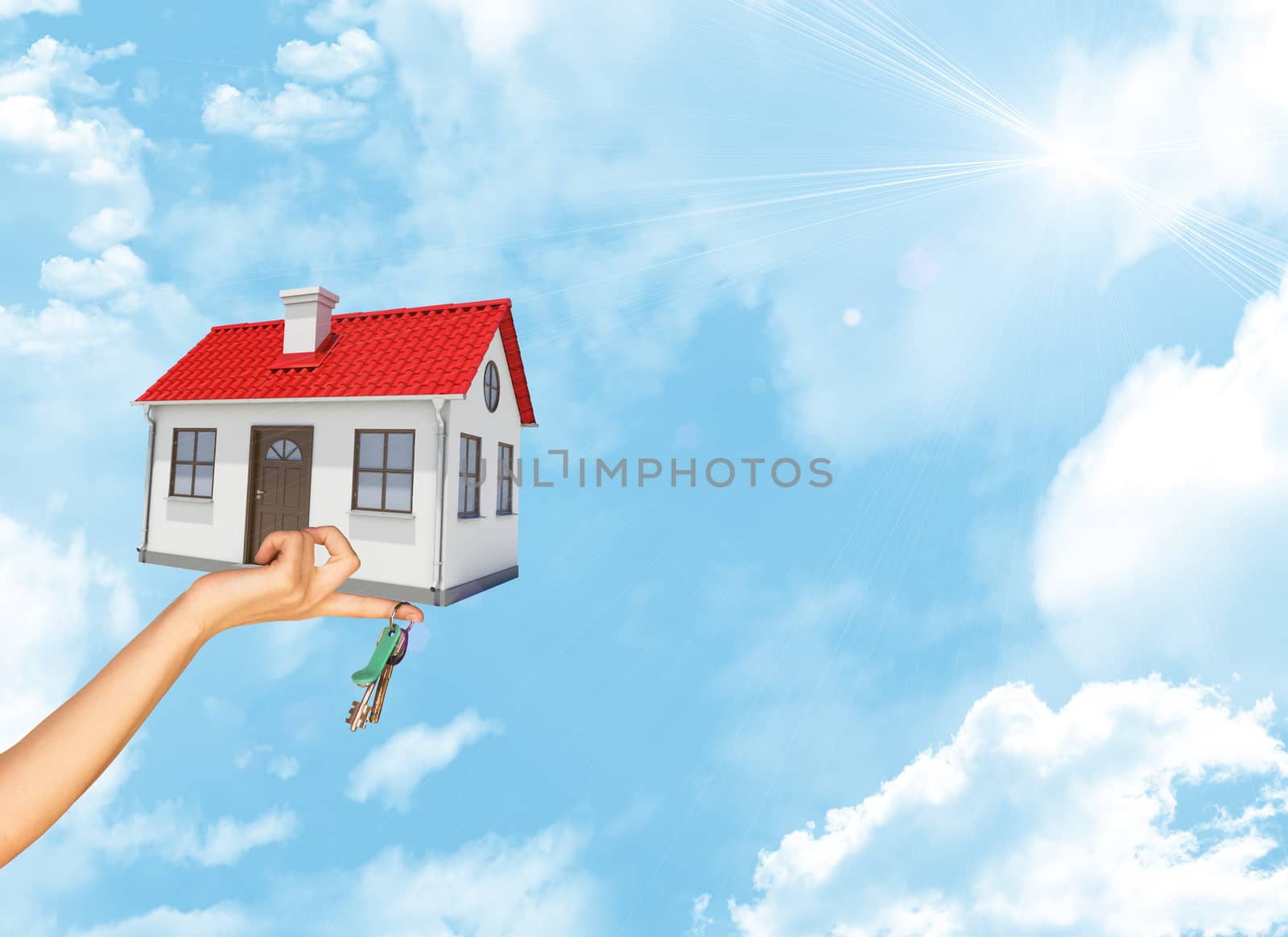 House and keys in businesswomans hand on blue sky background with bright sun