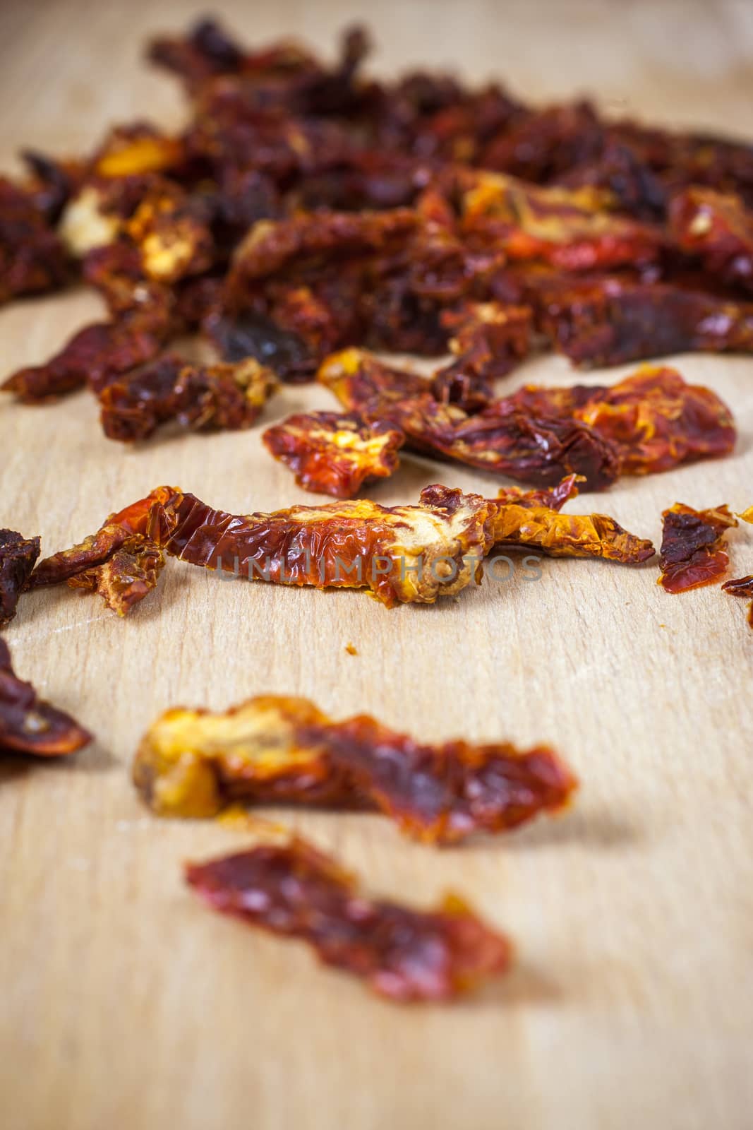 Sun dried tomatoes sliced up on a wooden cutting board.
