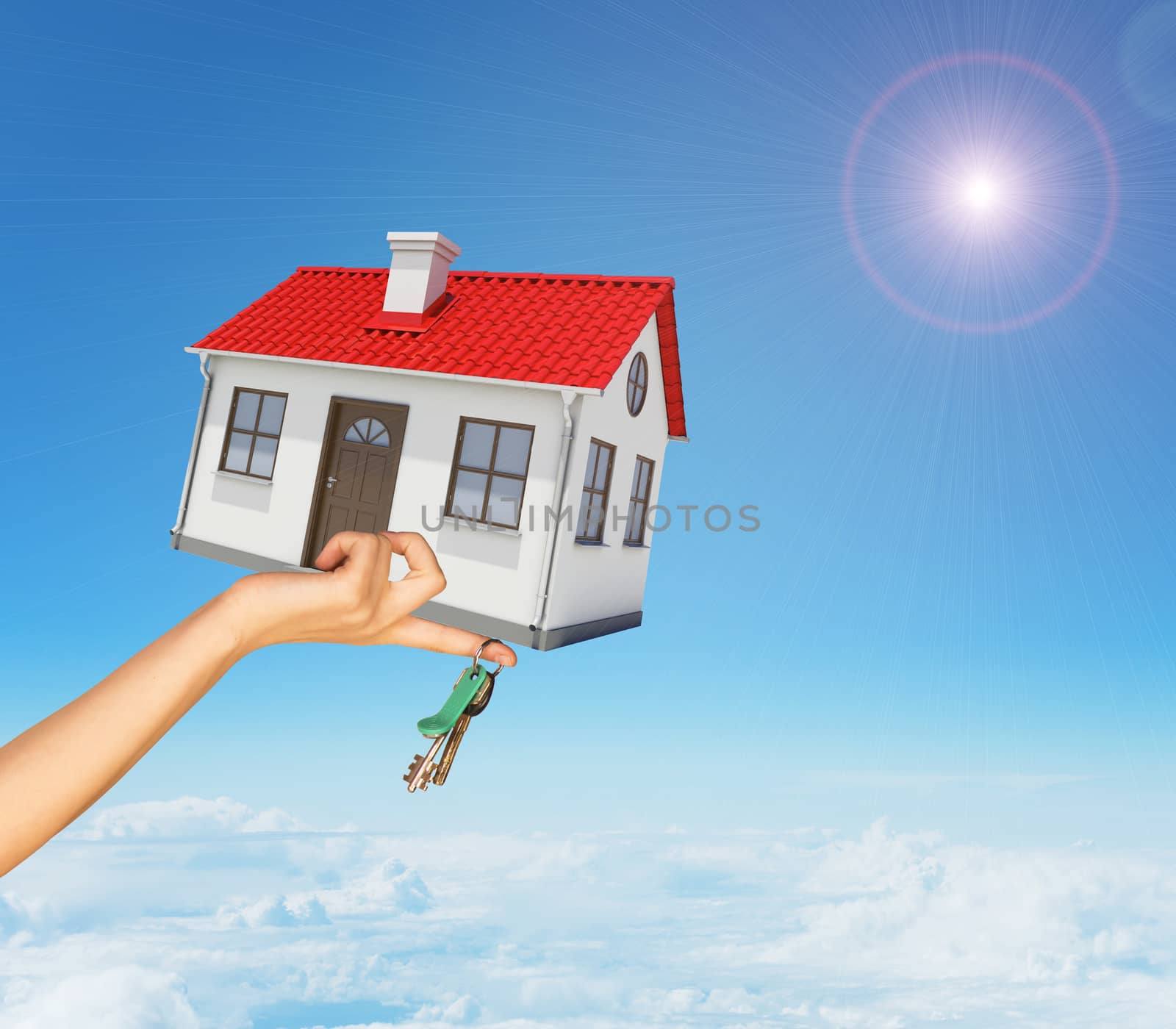 House and keys in womans right hand under clouds by cherezoff