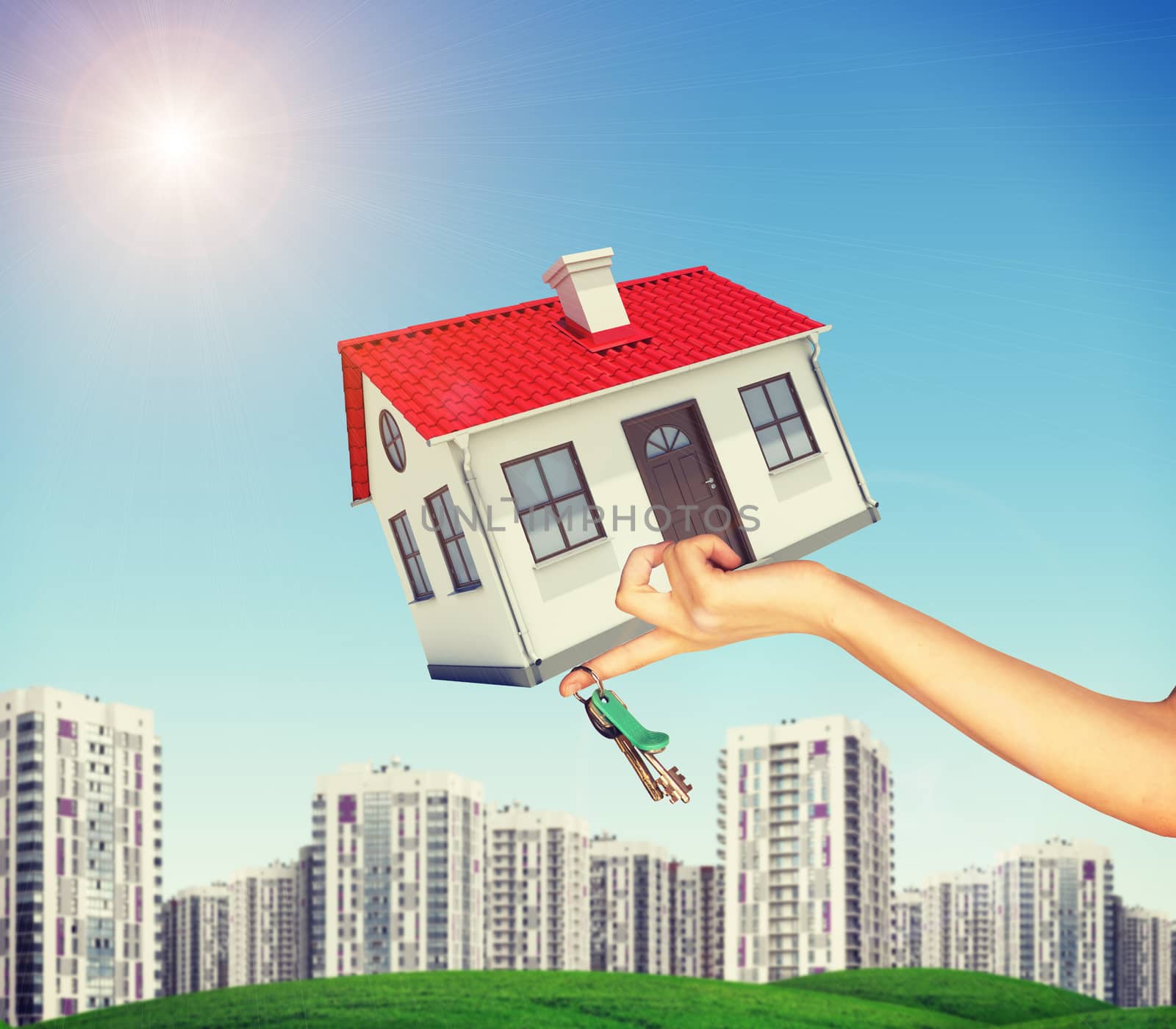 House and keys in businesswomans hand on cityscape background with blue sky
