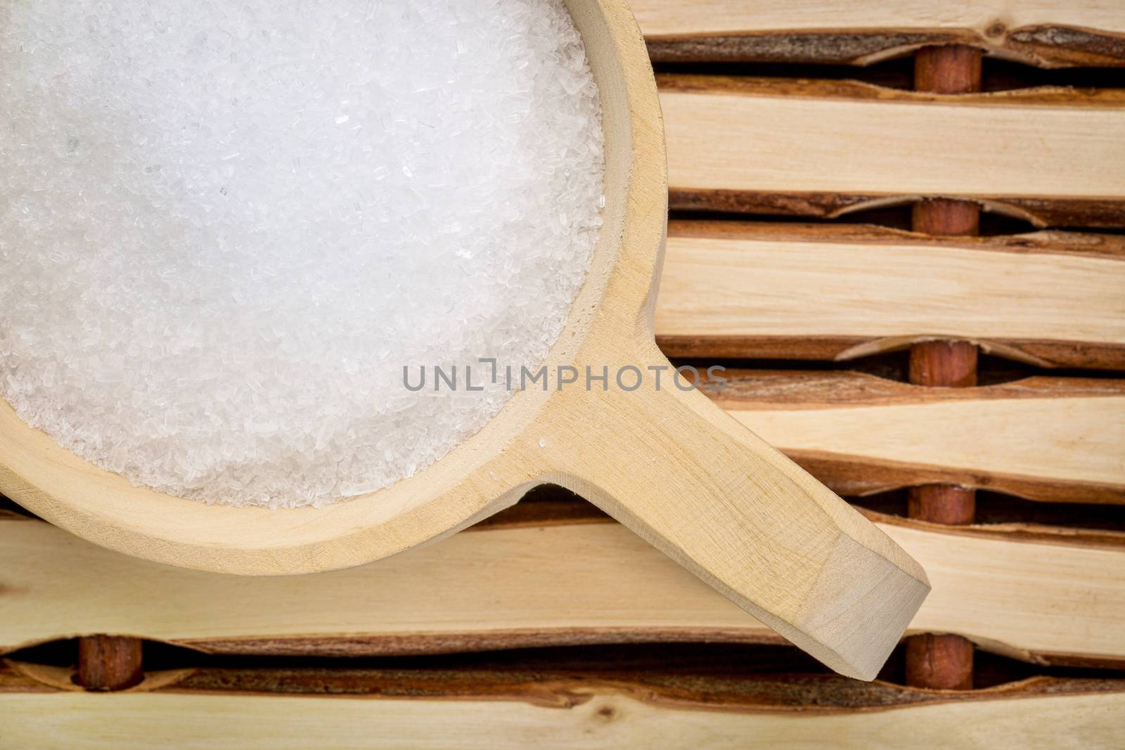 Magnesium sulfate (Epsom salts) in a rustic wooden scoop - relaxing bath concept