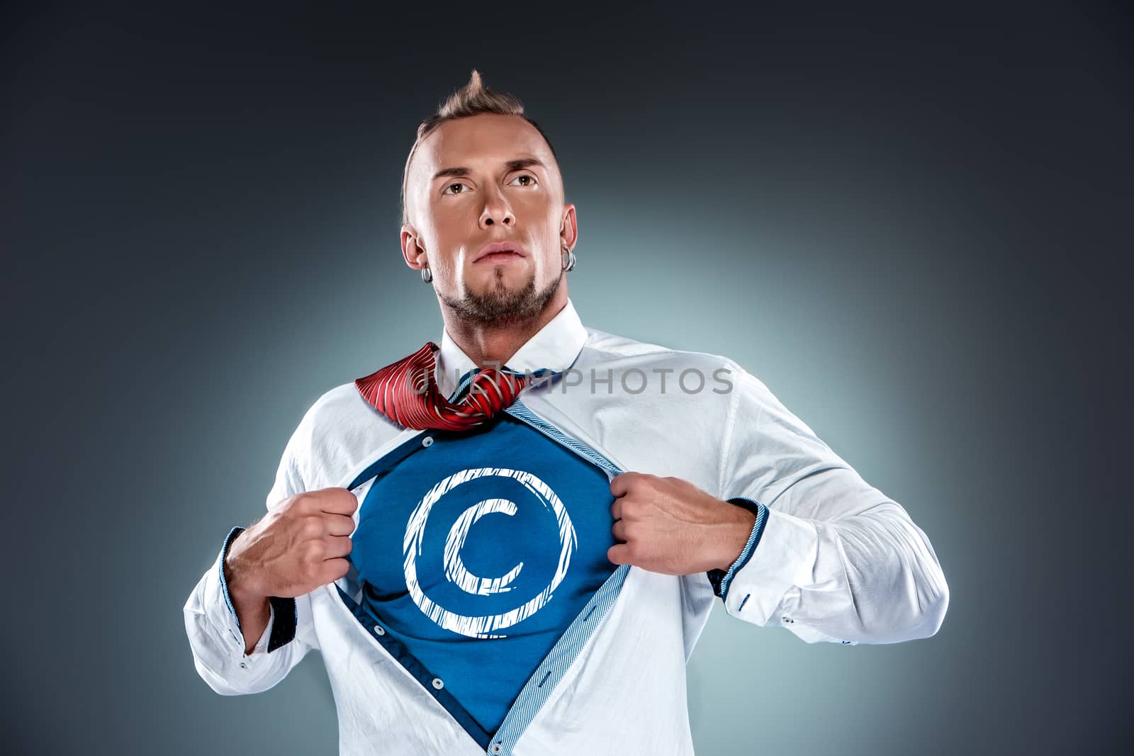 businessman acting like a super hero and tearing his shirt off on a gray background