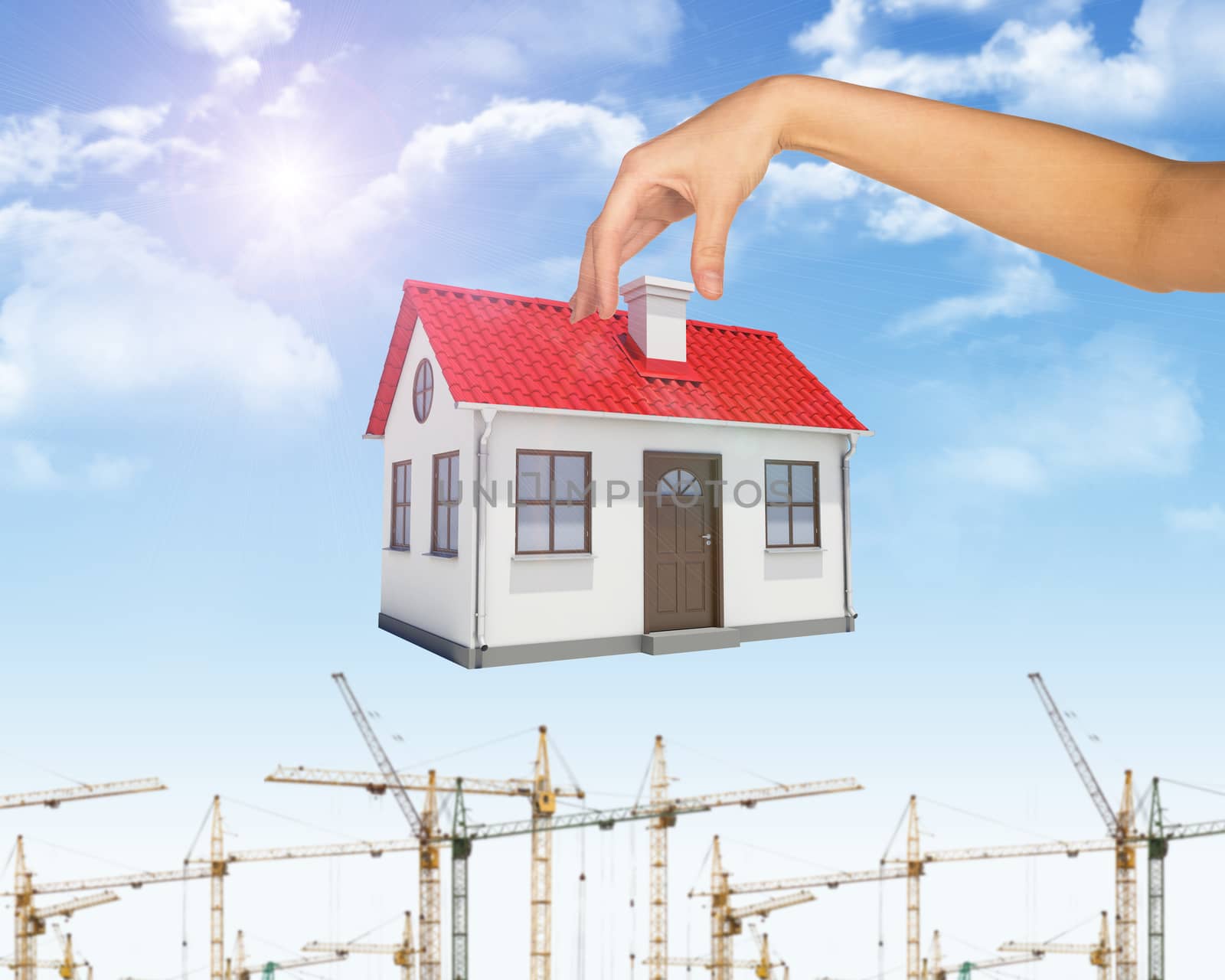 Businesswomans hand holding house for pipe on blue sky background with building cranes