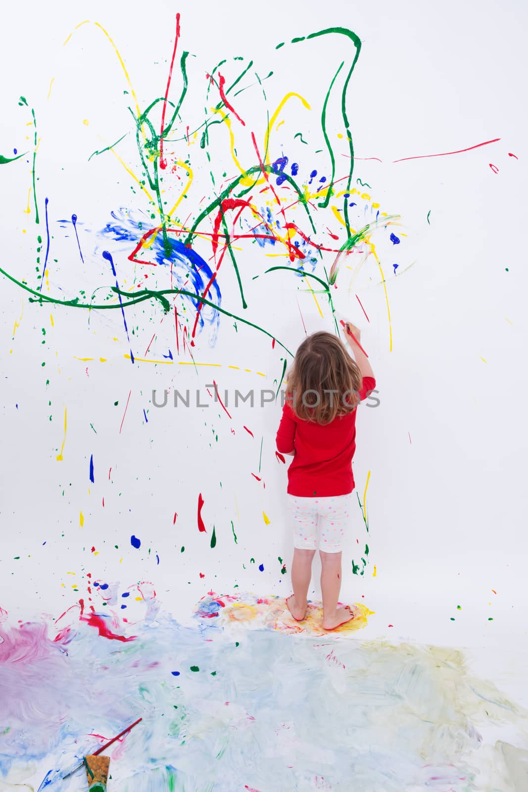 Young Little Kid Painting on White Big Wall by coskun