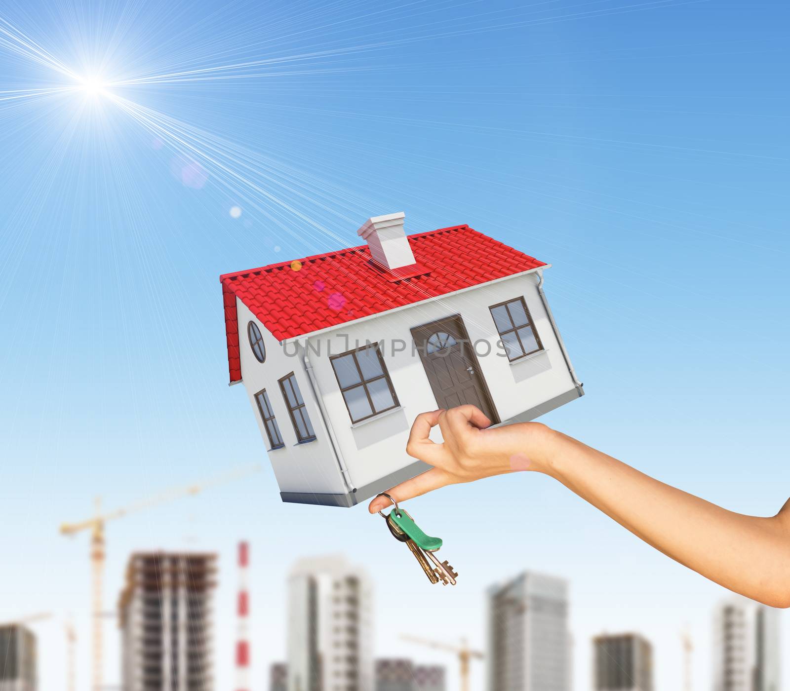 House in businesswomans left hand with cityscape on blue sky background 