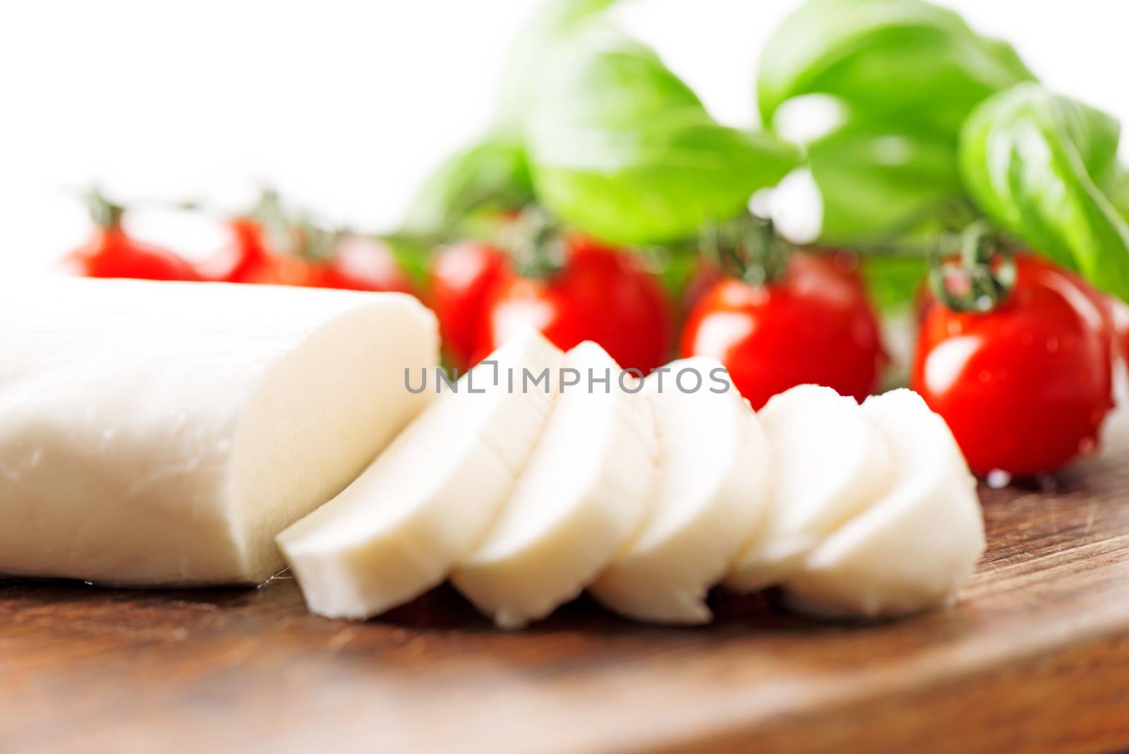 Ingredients for Caprese salad with mozzarella, tomato, basil and balsamic vinegar arranged on wooden table