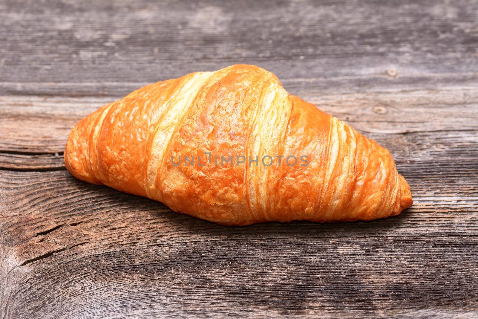 Fresh baked croissants on woodem table by comet