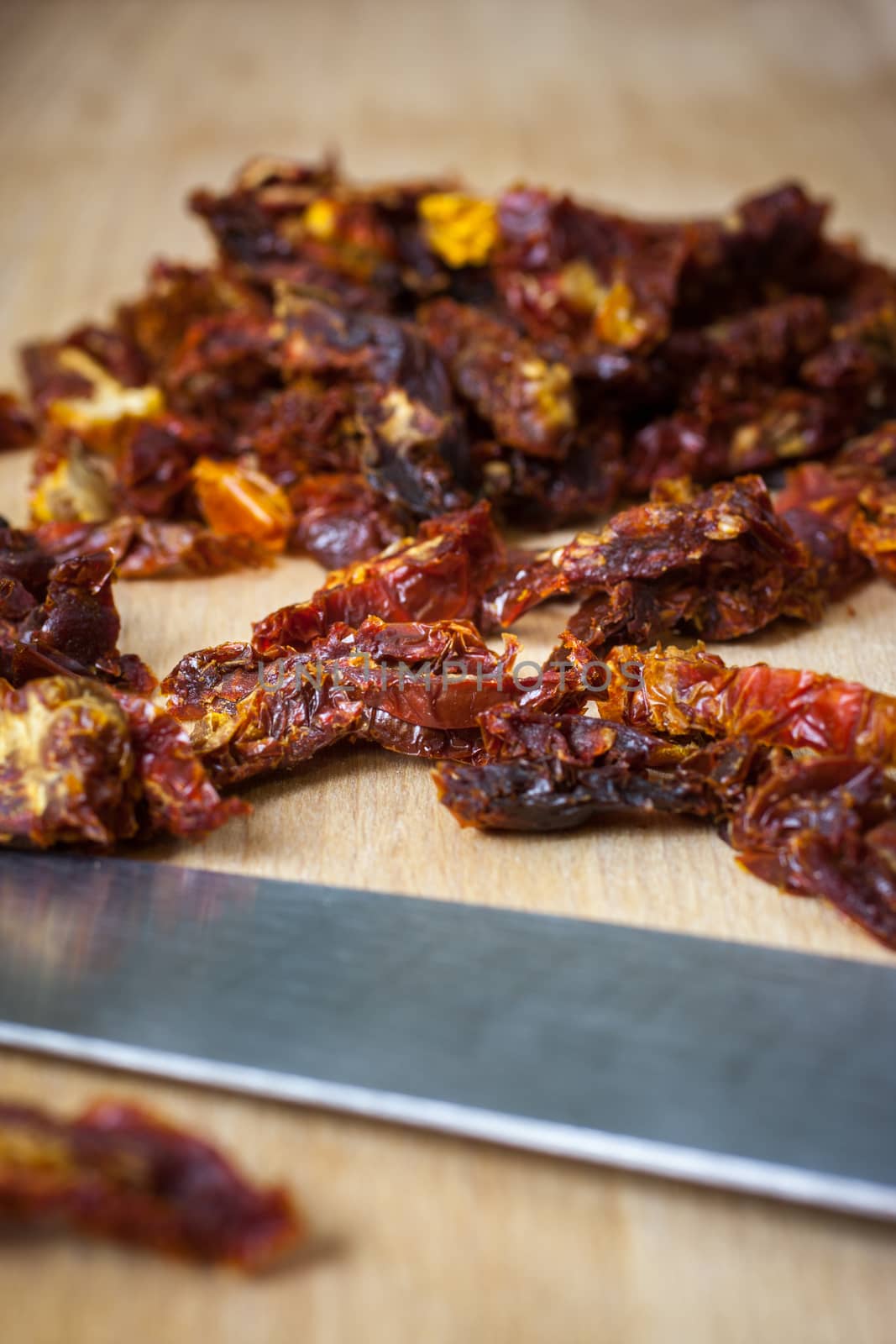 Sun dried tomatoes sliced up on a wooden cutting board.