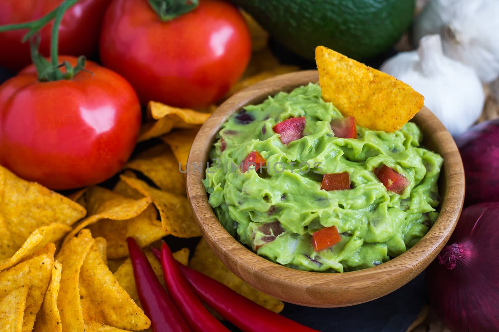 Guacamole in Wooden Bowl with Tortilla Chips and Ingredients