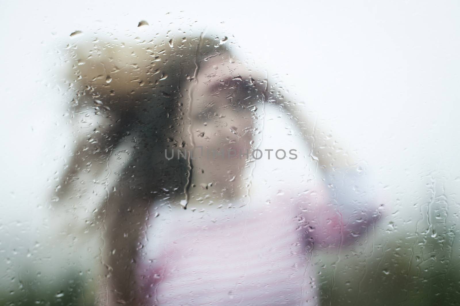 Blurry image of a woman through a rainy window